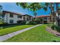 Condo building with red tile roof, mature trees, and well-manicured landscaping at 502 Hammock Pine Blvd # 502, Clearwater, FL 33761