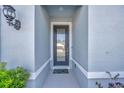 Inviting entryway featuring a modern front door, stylish sconce lighting, and a cheerful welcome mat at 6398 Bradford Woods Drive, Zephyrhills, FL 33542