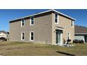 Back exterior of a tan home with a sliding glass door, grill, and small patio space at 7530 Broad Pointe Dr, Zephyrhills, FL 33540