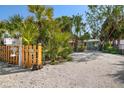 Welcoming gravel driveway entrance with palm trees, leading to a quaint home with a charming wooden fence at 8403 W Gulf Blvd, Treasure Island, FL 33706