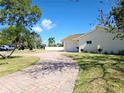 Inviting single-story home with a circular brick driveway, lush landscaping, and attached garage at 8719 Sunlit Cove Ne Dr, St Petersburg, FL 33702