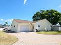 Welcoming single-story home with a brick driveway, attached garage, and beautifully landscaped yard at 8719 Sunlit Cove Ne Dr, St Petersburg, FL 33702