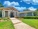 Inviting home featuring a stone facade, a covered porch with white columns, and manicured landscaping at 898 Cypress Lakeview Ct, Tarpon Springs, FL 34688