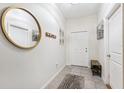 Inviting entryway with neutral tile, a round mirror, and storage bench at 10687 Lake Montauk Dr, Riverview, FL 33578