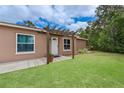 Inviting single-story home entryway with manicured lawn and pergola at 11396 Terrell Rd, Spring Hill, FL 34608