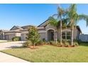 Inviting single-story home with a three-car garage and beautiful landscaping, creating a welcoming atmosphere at 11407 Acacia Grove Ln, Riverview, FL 33579