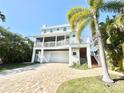 Lovely elevated coastal home with a brick paver driveway and lush, tropical landscaping at 16204 3Rd E St, Redington Beach, FL 33708