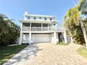 Charming coastal home featuring a two-car garage, a screened porch and a brick paver driveway at 16204 3Rd E St, Redington Beach, FL 33708