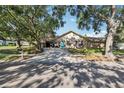 Attractive ranch-style home with an attached garage, large driveway, mature shade trees, and appealing blue front door at 170 Foxfire Ln, Oldsmar, FL 34677
