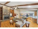 Spacious living room featuring a stone fireplace, wood ceiling beams, hardwood floors, and open kitchen at 170 Foxfire Ln, Oldsmar, FL 34677
