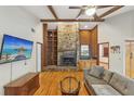 Bright living room featuring vaulted ceilings with wood beams, a stone fireplace, and hardwood flooring at 170 Foxfire Ln, Oldsmar, FL 34677