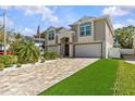 Attractive two-story home with a paver driveway, lush grass, and double-car garage at 314 Crosswinds Dr, Palm Harbor, FL 34683