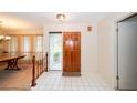 Bright foyer featuring tile flooring, a wooden front door, and a glimpse into the dining area at 34527 Cedarfield Dr, Dade City, FL 33523