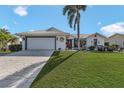 Well-maintained single-story home with a decorative front lawn, tropical landscaping, and an attached two-car garage at 3819 Barnegat Dr, Punta Gorda, FL 33950