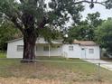 A single-story house with a white exterior, a porch, and a large tree in the yard at 3918 E Clifton St, Tampa, FL 33610