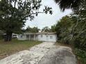 A single-story home featuring a white exterior, a porch, and a cracked concrete driveway at 3918 E Clifton St, Tampa, FL 33610