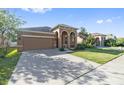 Charming stucco home featuring a two-car garage, arched entryway, and well-manicured lawn at 5108 Suncatcher Dr, Wesley Chapel, FL 33545