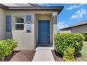 Inviting front entryway with a blue door, neat landscaping, and a 'hello' welcome mat at 7236 Salt River Ave, Sun City Center, FL 33573