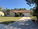 Welcoming single-story home with a long driveway, attached garage, and textured stone front at 8718 Arrowhead Dr, Hudson, FL 34667