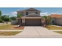 Charming two-story home with a well-maintained lawn and driveway, accentuated by lush palm trees at 10645 Laguna Plains Dr, Riverview, FL 33578