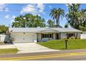 Charming single-story home with a manicured lawn, metal roof, and attached two-car garage at 1414 Sunset Ln, Lutz, FL 33549