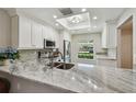 Bright kitchen featuring white cabinets, stainless steel appliances, and beautiful stone countertops at 1535 Nursery Rd # 111, Clearwater, FL 33756