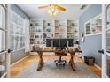 Bright home office with custom built-in shelving, hardwood floors, and a modern desk setup at 19139 Cypress Reach Ln, Tampa, FL 33647