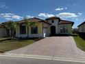 Inviting yellow home with a brick driveway, 2-car garage, and neat landscaping, under a sunny sky with scattered clouds at 2217 5Th E St, Palmetto, FL 34221