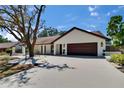 A beautifully renovated white brick home featuring a brown roof, a 2-car garage, and professional landscaping at 3004 Rolling Acres Pl, Valrico, FL 33596