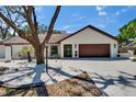 Exterior view of a home with a 2 car garage, a brown roof, and updated landscaping at 3004 Rolling Acres Pl, Valrico, FL 33596