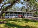 Charming home exterior with mature trees, a wrap around porch, and lush landscaping at 5870 Jim Davis Rd, Parrish, FL 34219