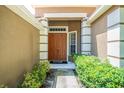 Inviting entryway featuring a solid wood front door, sidelight window, and colorful foliage at 6130 Whimbrelwood Dr, Lithia, FL 33547