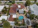 Aerial view of a backyard featuring a pool, patio, lush tropical landscaping, and a detached garage at 806 Narcissus Ave, Clearwater Beach, FL 33767