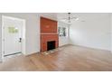 Bright living room featuring an orange-tiled fireplace, modern lighting, and light wood flooring at 108 5Th St, Belleair Beach, FL 33786