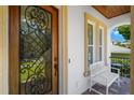 Elegant front door with decorative ironwork, sidelight, and covered porch with bench seating at 108 Bermuda Ave, Tampa, FL 33606