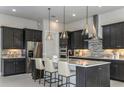 Elegant kitchen with dark cabinetry, stainless appliances, a center island, and modern pendant lights at 11432 Shoreline Trl, Parrish, FL 34219