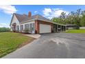 Rear of the house with an attached garage, screened porch, brick accents, and a paved driveway at 12345 Citrus Way, Brooksville, FL 34601