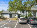 Exterior view with guest parking, a manicured lawn and mature landscaping around the gray townhome at 1303 N Mcmullen Booth Rd # 1303, Clearwater, FL 33759