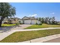 Landscaped home with a three car garage and a brick paved driveway in a suburban neighborhood at 13355 Palmerston Rd, Riverview, FL 33579
