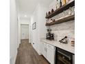 Stylish hallway featuring a bar area with a wine fridge, a white stone backsplash, and floating shelves at 13355 Palmerston Rd, Riverview, FL 33579