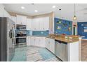 Bright kitchen with stainless steel appliances, white cabinets, granite countertops, and stylish blue backsplash at 1505 Trailwater St, Ruskin, FL 33570