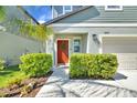 Inviting front entrance featuring a vibrant red door, trimmed shrubbery, and manicured green lawn at 22223 Storybook Cabin Way, Land O Lakes, FL 34637