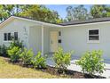 Inviting front entrance with a sunny yellow door, lush landscaping, and fresh neutral paint at 2274 66Th S Ave, St Petersburg, FL 33712
