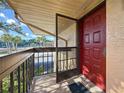 Red condo front door with black screen overlooking a community pool and mature trees at 2685 Sabal Springs Cir # 201, Clearwater, FL 33761