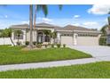 Well-maintained single-story home featuring a lush green lawn, palm trees, and a spacious three-car garage at 2816 Pankaw Ln, Valrico, FL 33596