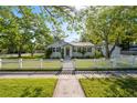 Charming single-story home with a white picket fence, lush lawn, and mature shade trees at 317 N Washington Ave, Clearwater, FL 33755