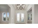 Bright foyer featuring a decorative light fixture, a glass front door, and windows at 5325 San Remo Cir, Wimauma, FL 33598
