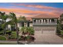 Beautiful home with a terracotta roof and meticulously landscaped front yard, complemented by a vibrant sunset backdrop at 6461 Rubia Cir, Apollo Beach, FL 33572
