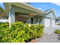 Inviting front porch with a swing and ceiling fan, surrounded by lush landscaping at 6745 Basswood Cir, Zephyrhills, FL 33542