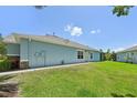 Side view of a light blue single-story home with a green lawn and a glimpse of a screened-in patio at 7413 Surrey Wood Ln, Apollo Beach, FL 33572